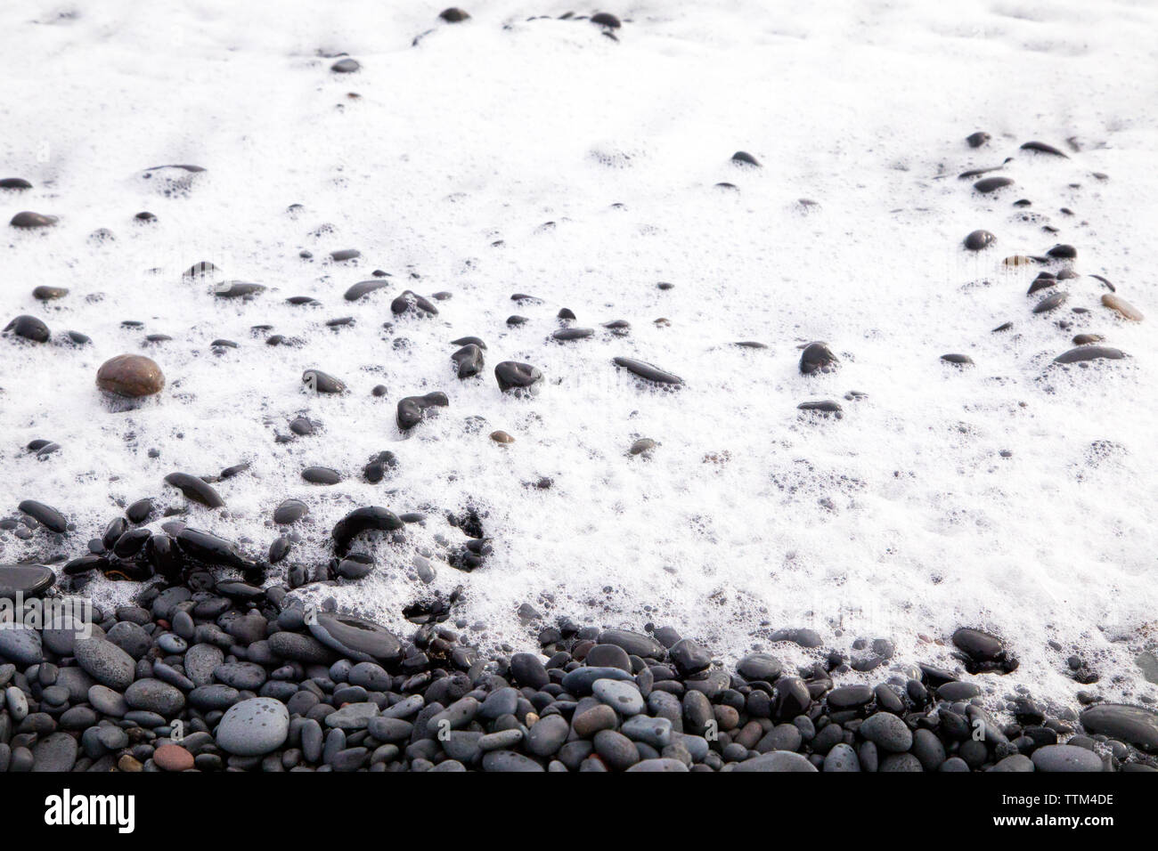 Ocean Wave Schaum über Steine am Strand Reynisfjara Island Stockfoto