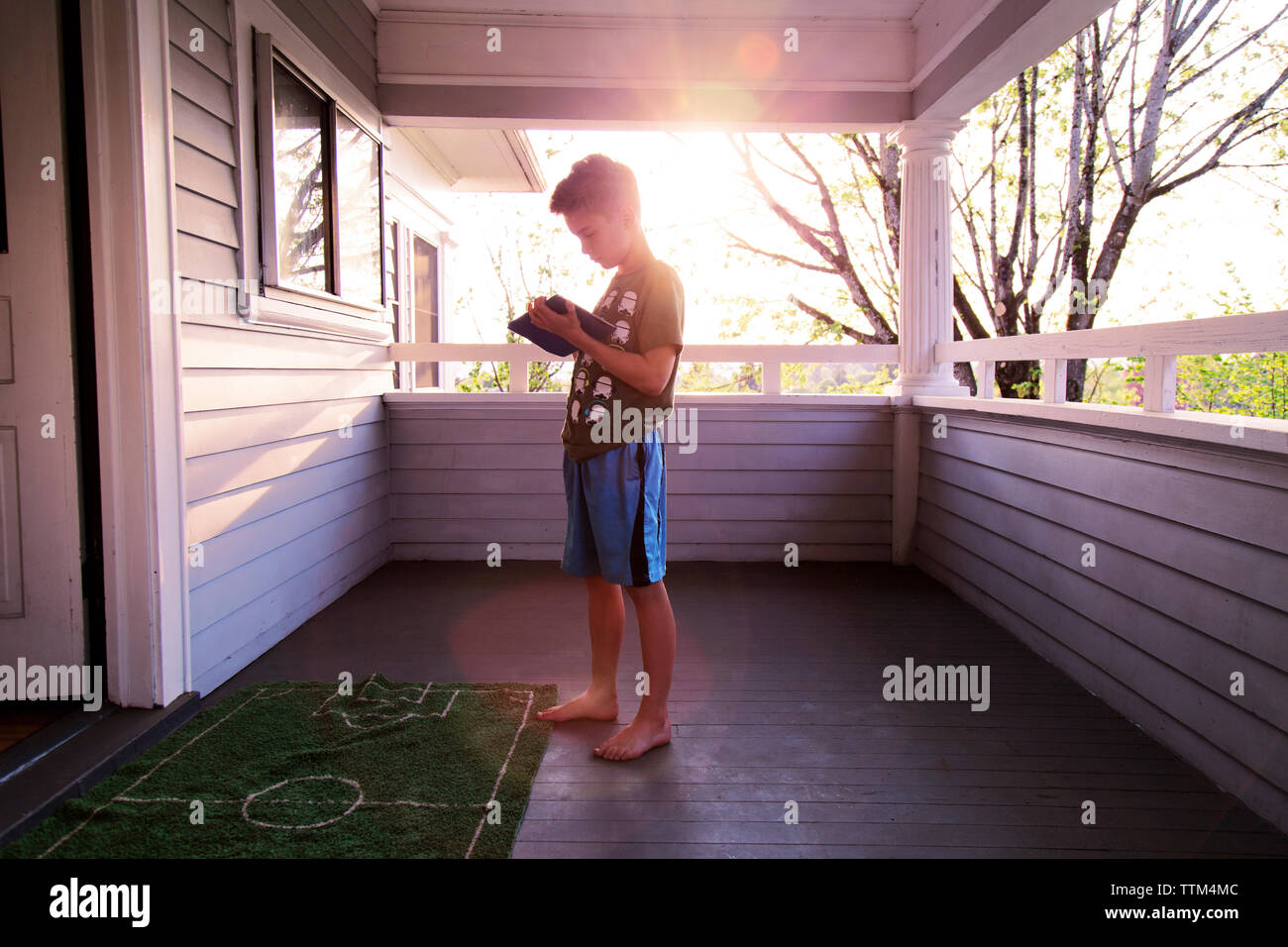 Junge spielt Spiel auf Tablet Computer an der Veranda Stockfoto