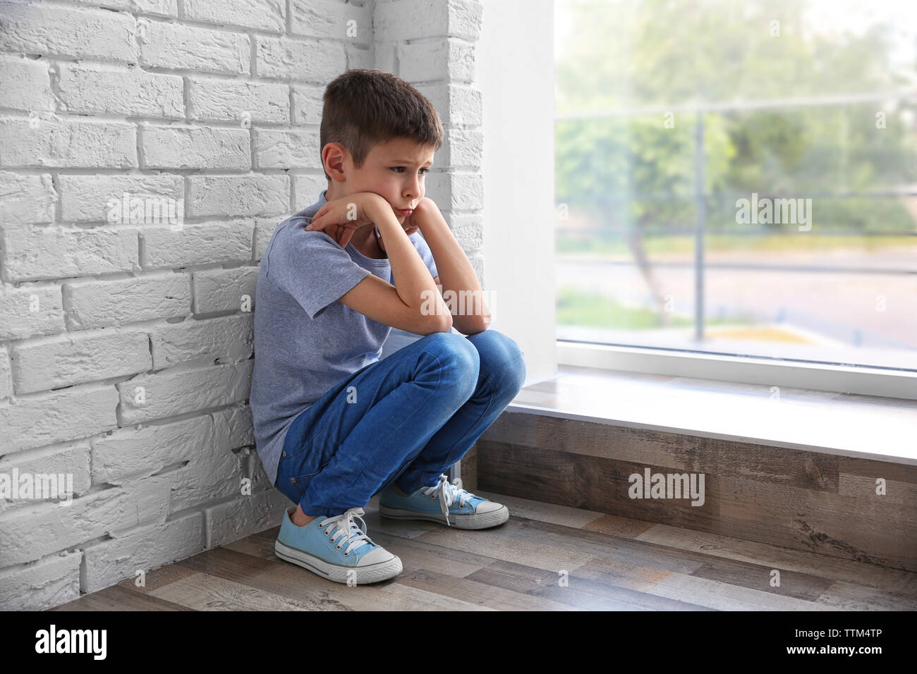 Traurige Junge sitzt in der Nähe der Fenster Stockfoto