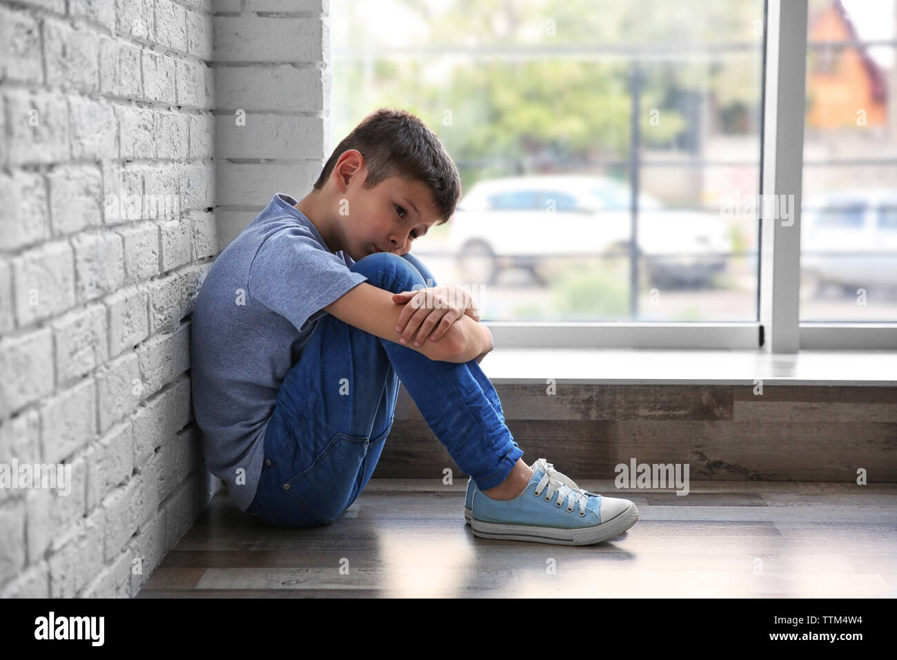 Traurige Junge sitzt in der Nähe der Fenster Stockfoto