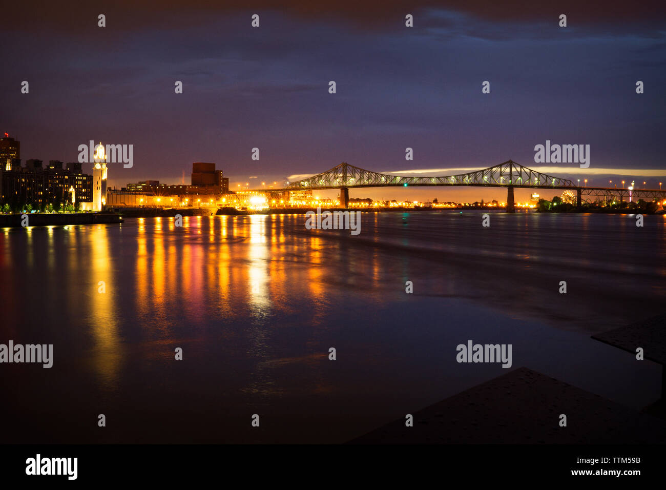 Beleuchtete Brücke über den Fluss in der Nacht Stockfoto