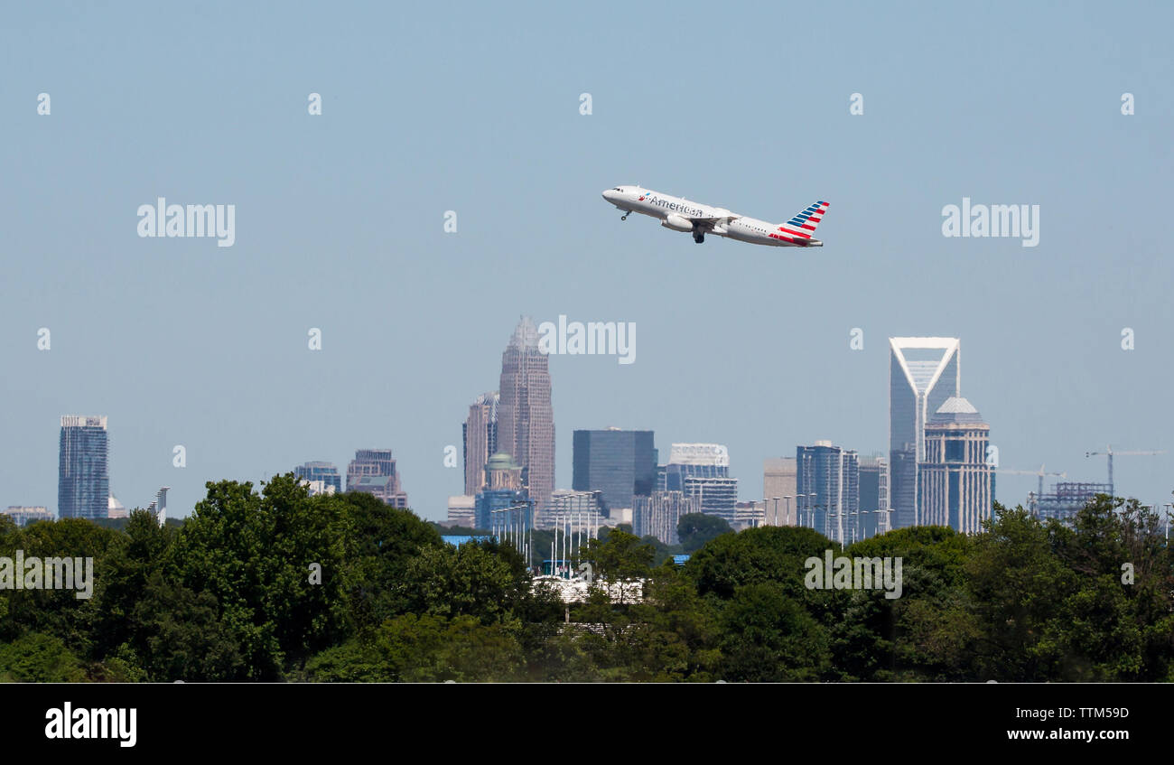 Ein American Airlines Commercial jet zieht aus internationalen Flughafen Charlotte-Douglas mit der Charlotte Skyline im Hintergrund. Stockfoto