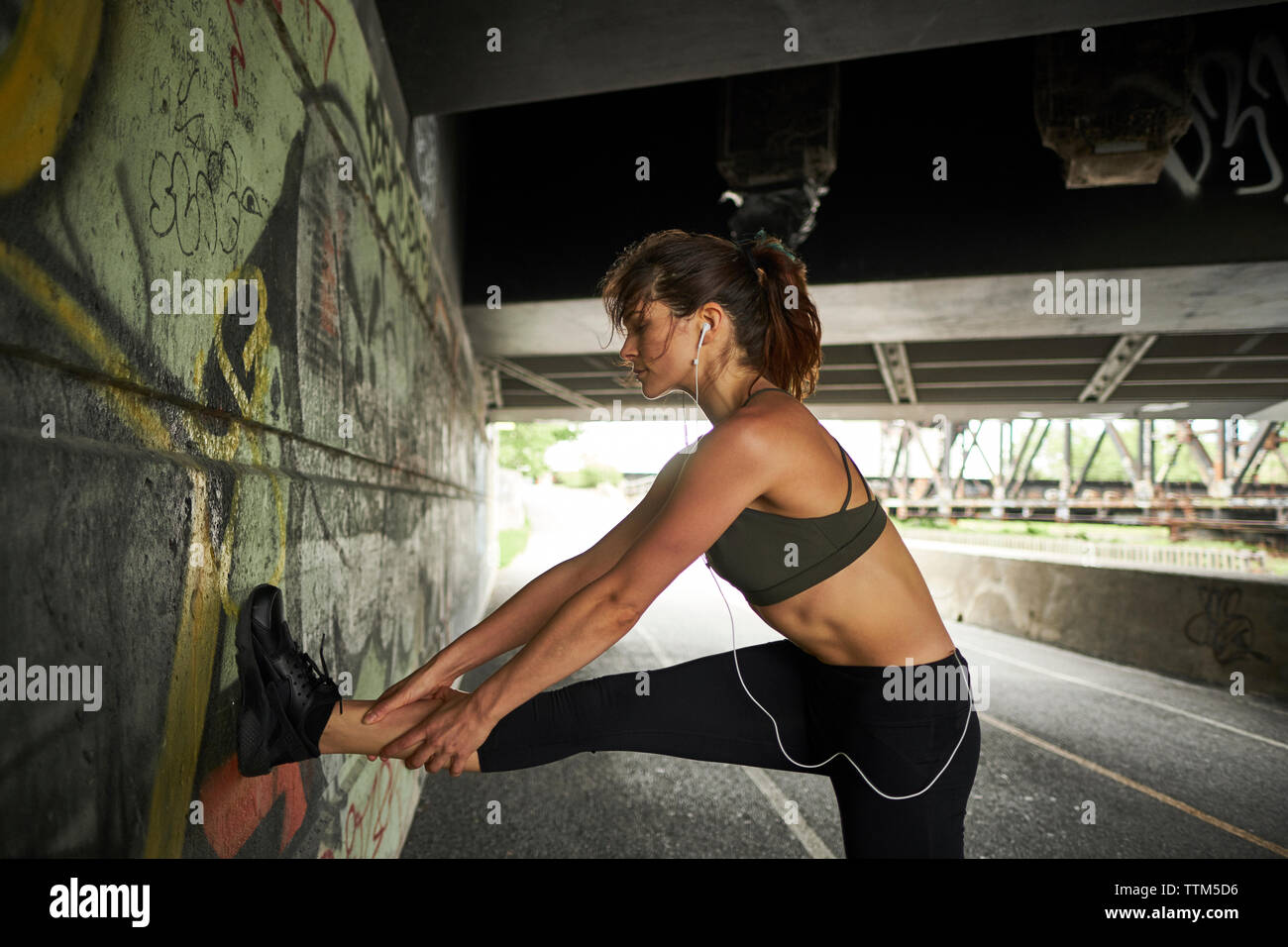 Frau stretching Bein auf Graffiti an der Wand während der Ausübung Stockfoto