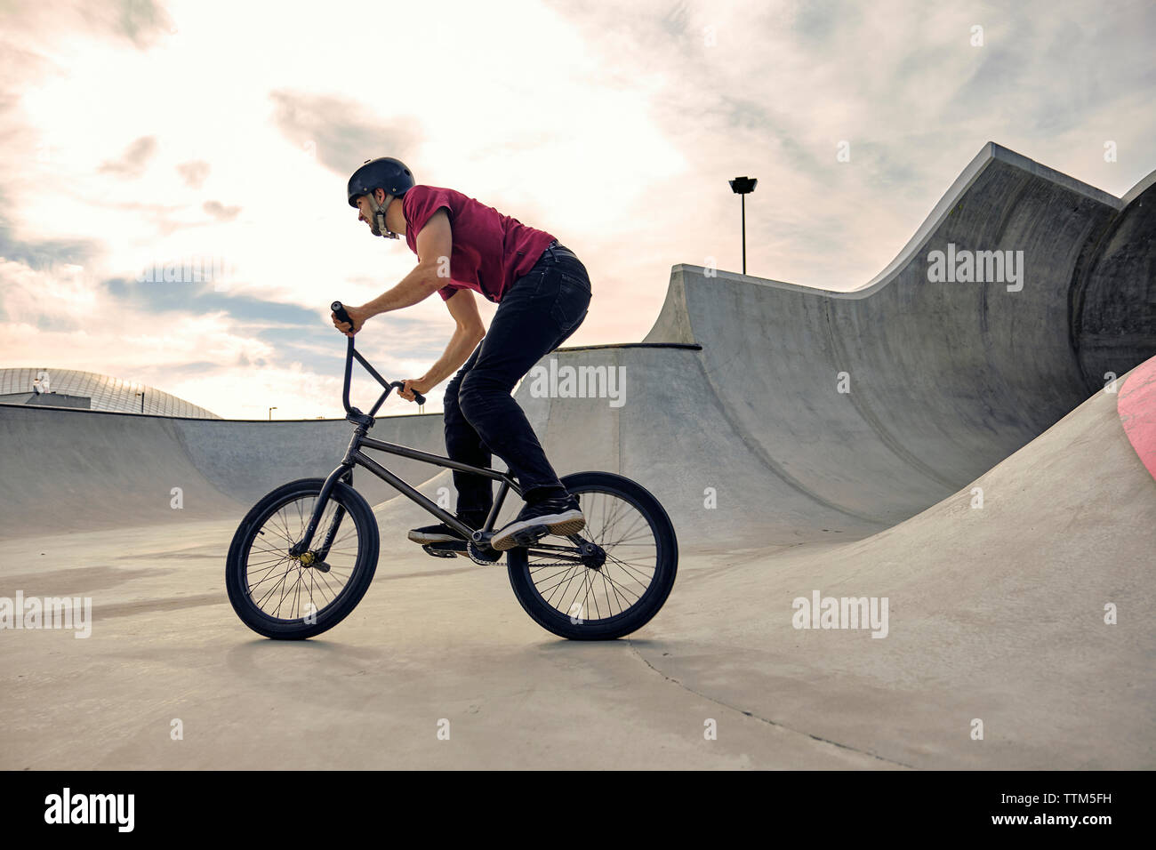 Reiter BMX Fahrrad auf konkreten Rampe gegen bewölkter Himmel bei skateboard Park Stockfoto