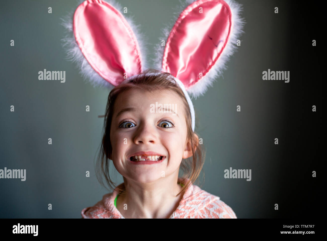 Portrait von verspielten Mädchen mit hasenohren kopfband und zeigt zur Lücke zu Hause Zahnriemen Stockfoto