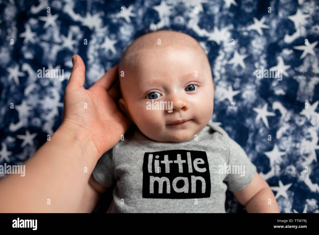 7/8 Hand der Mutter mit Sohn Kopf auf die Matratze Stockfoto