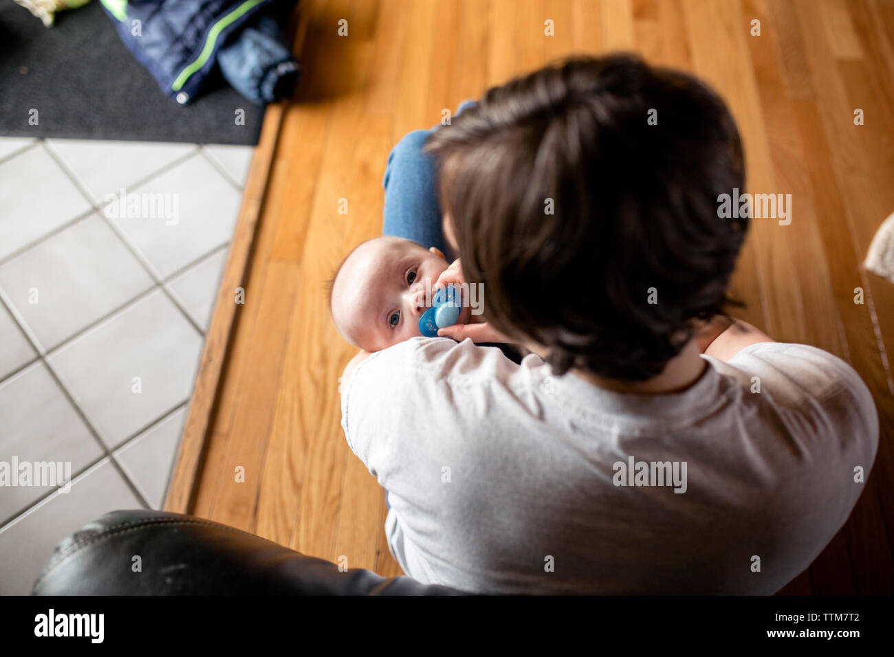 Hohe Betrachtungswinkel von Mutter Holding niedlichen Sohn sitzend auf Parkett zu Hause Stockfoto