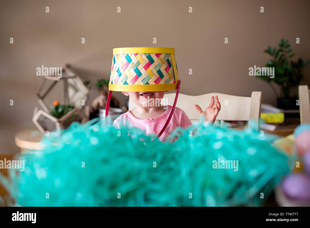 Mädchen mit Korbkorb auf dem Kopf, das zu Hause zu ostern steht Stockfoto