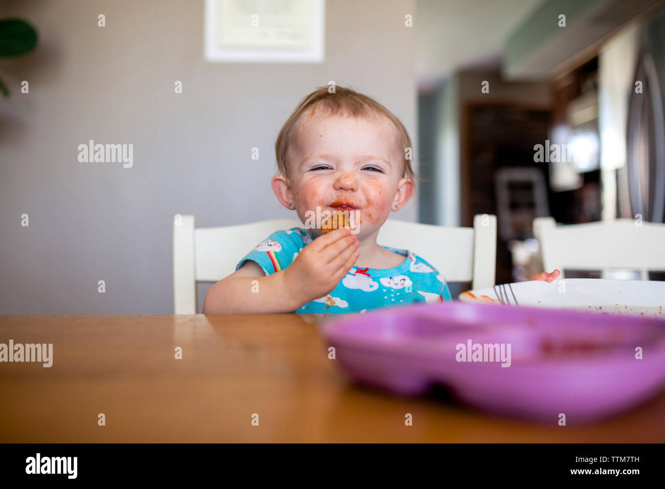 Portrait von Baby Mädchen Essen während der Sitzung von Tisch zu Hause Stockfoto