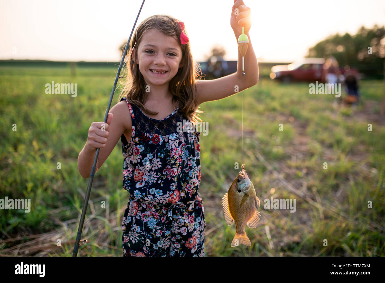Portrait von lächelnden Mädchen, dass tote Fische in der Linie auf dem Feld bei Sonnenuntergang Stockfoto