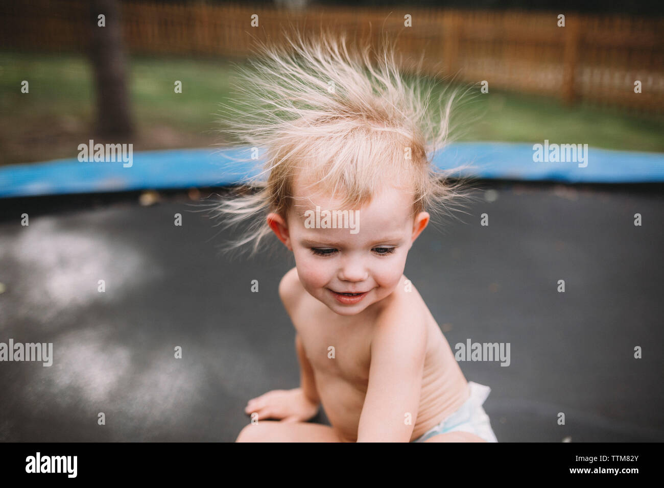 Kleinkind Mädchen auf Trampolin mit statischen blond unordentlichen Haar Stockfoto