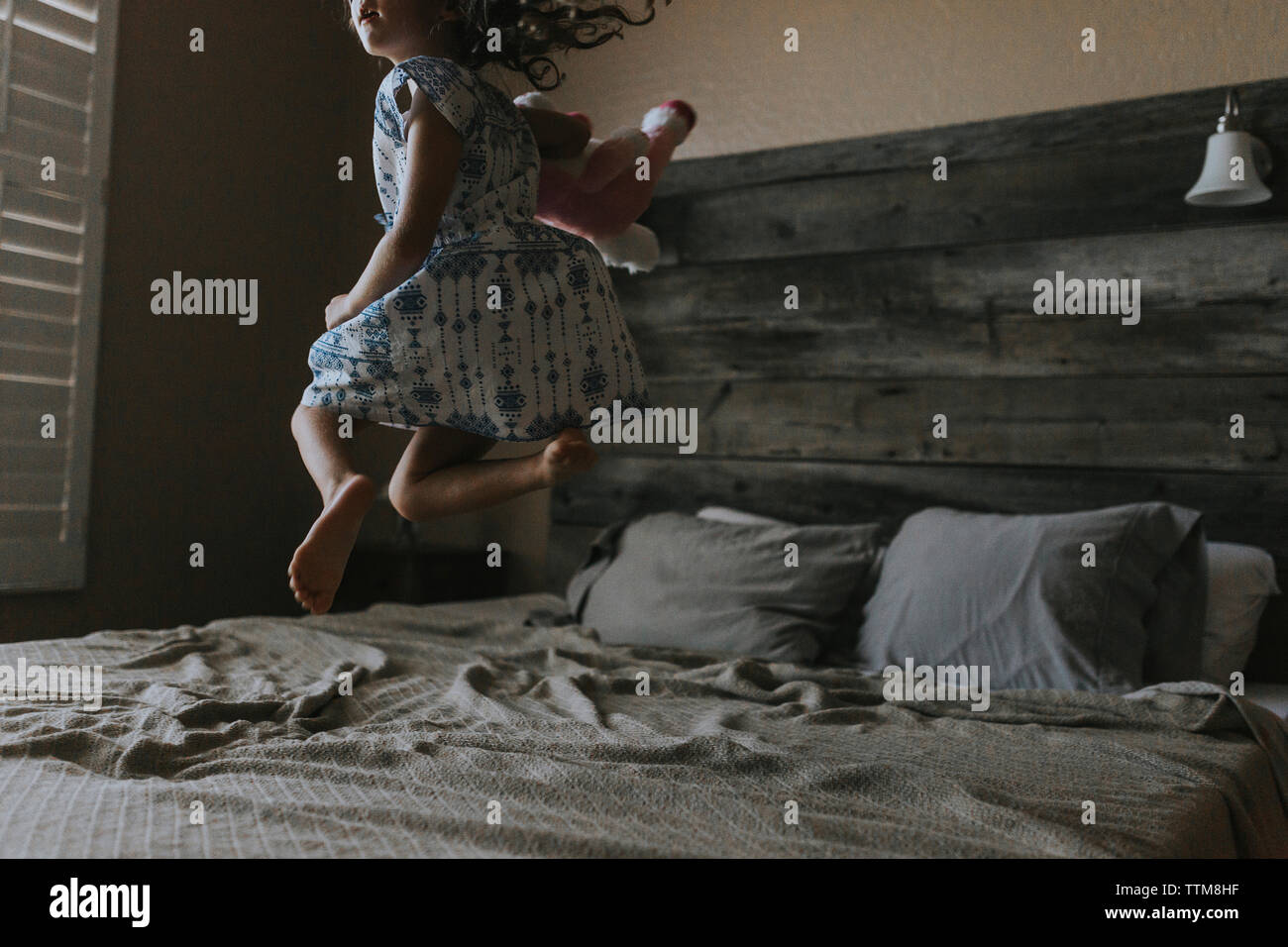 Fröhliches Mädchen springen auf Bett zu Hause Stockfoto