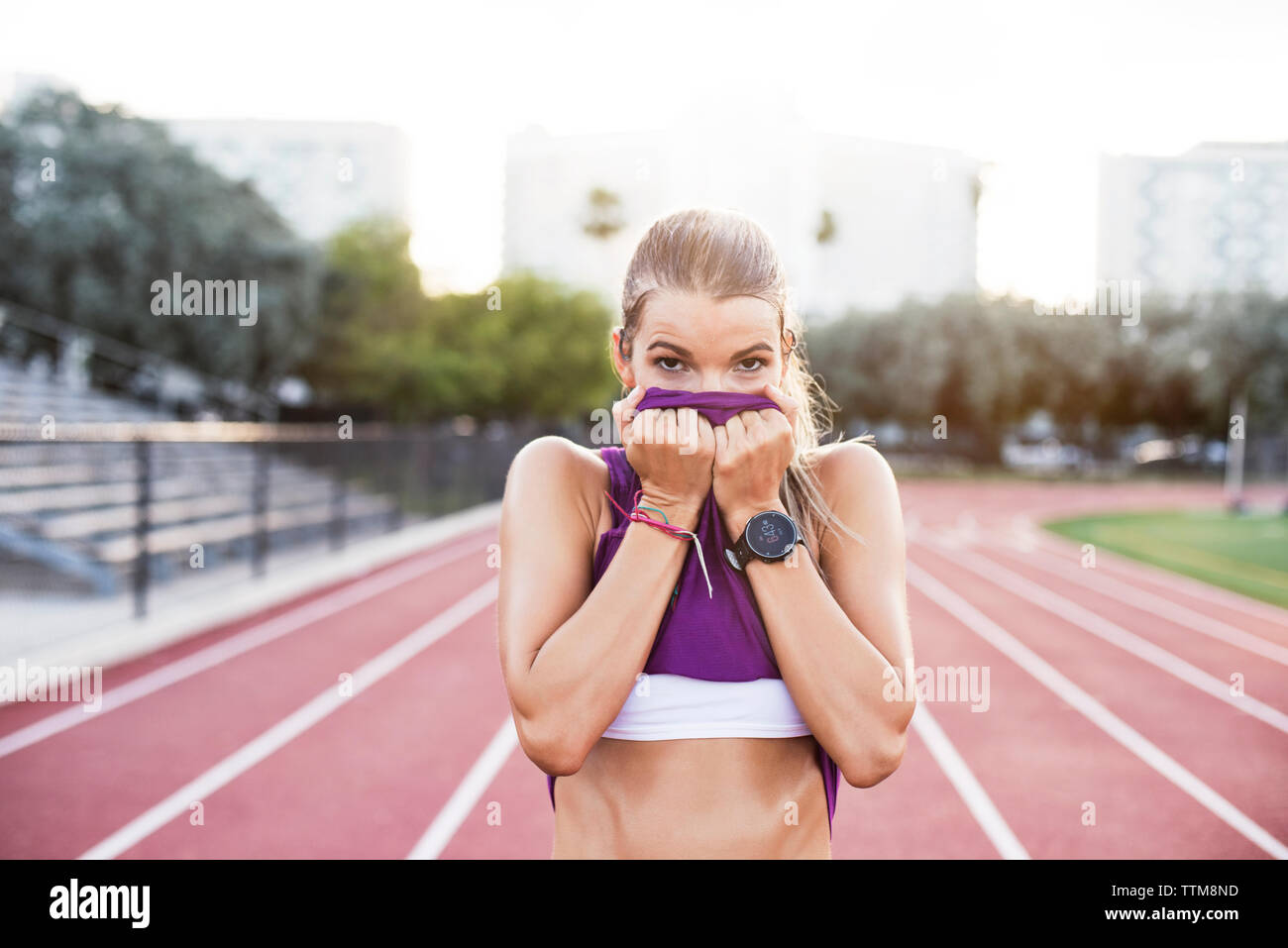 Portrait von sportlichen Frau wischen Schweiß im Gesicht mit Tank Top in das Feld Stockfoto