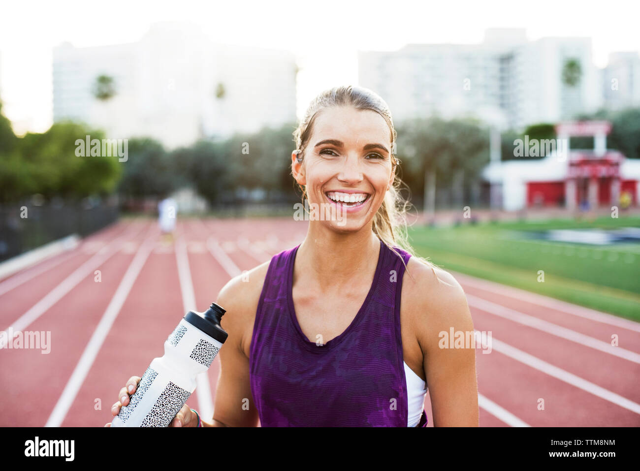 Portrait von Happy woman holding Wasserflasche auf der Rennstrecke Stockfoto