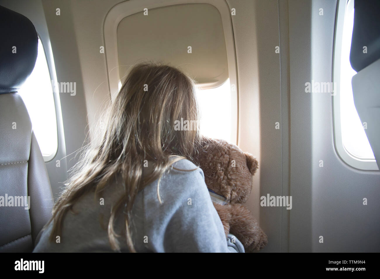 Ansicht der Rückseite des Mädchen mit teddybär Blick durch Fenster, während im Flugzeug Stockfoto