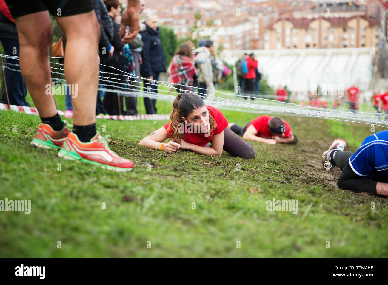Frau kriecht unter Stacheldraht beim Sport Rennen Stockfoto