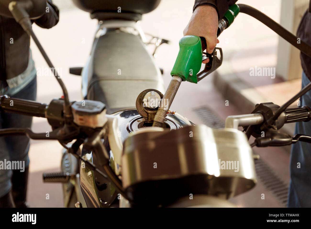 Zugeschnittenes Bild von Senior biker Motorrad tanken an der Tankstelle Stockfoto