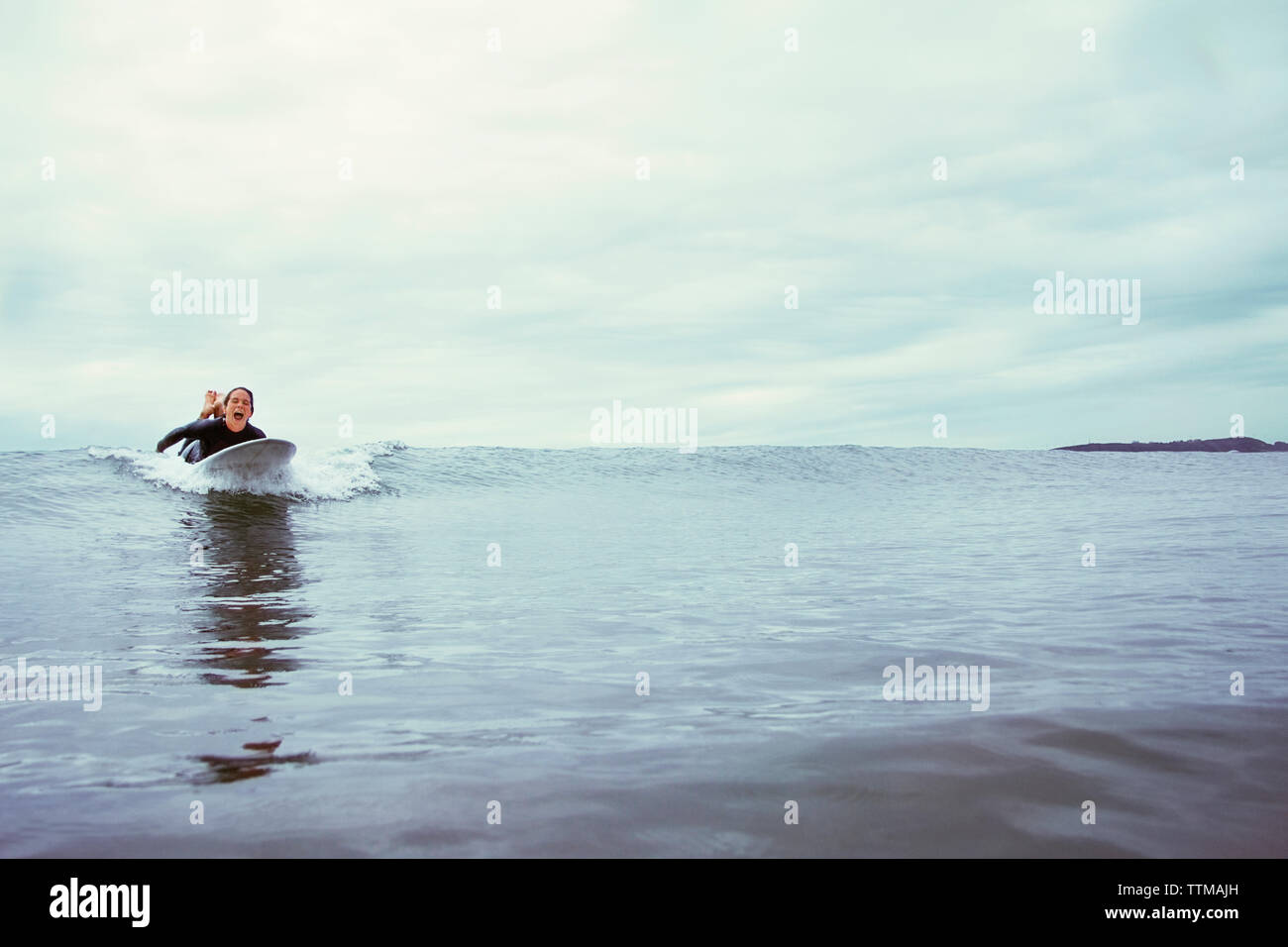 Junge Frau Surfen am Meer gegen bewölkter Himmel aufgeregt Stockfoto