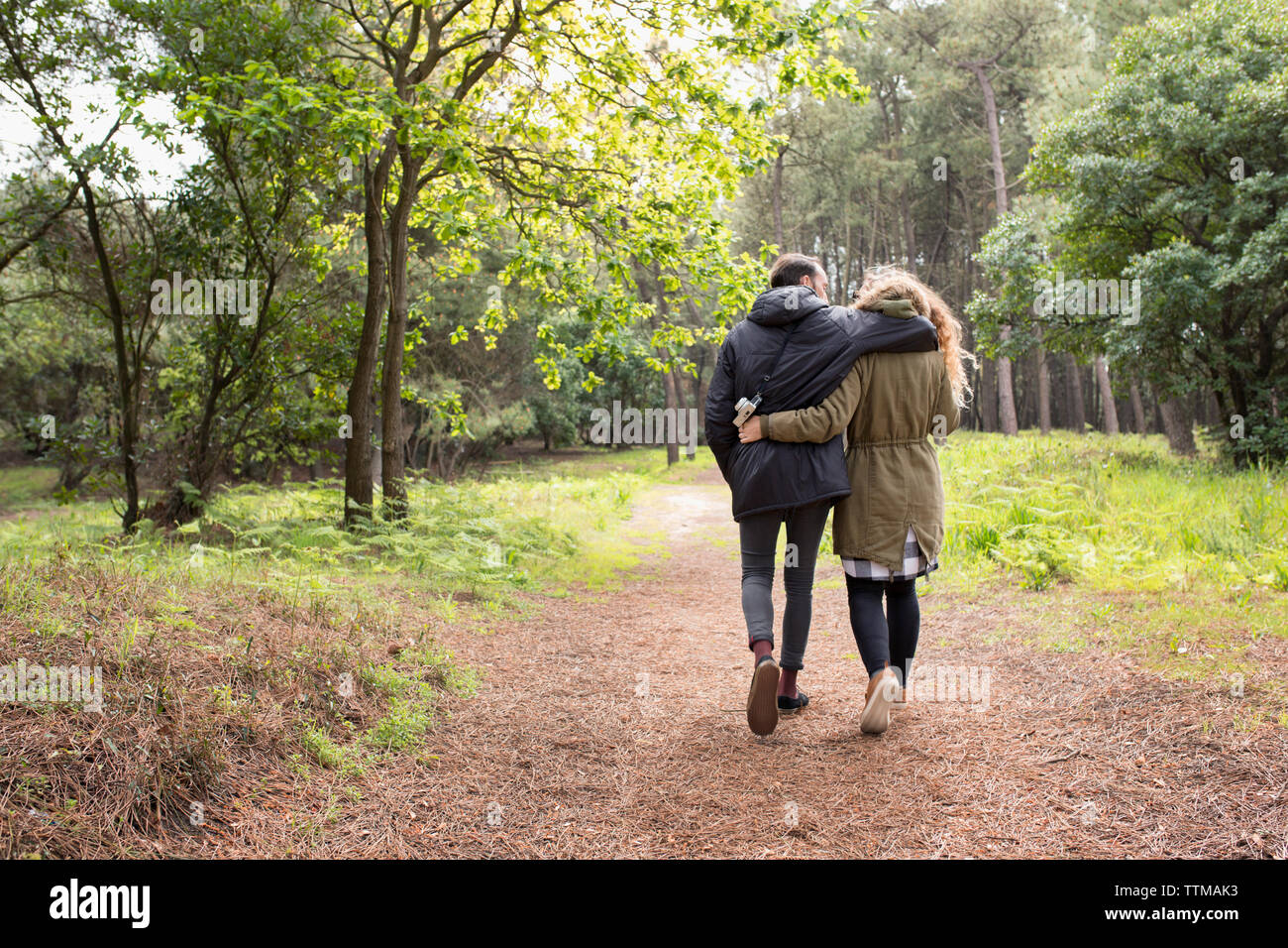 Ansicht der Rückseite des Romantisches Paar mit Arme um Walking im Wald Stockfoto