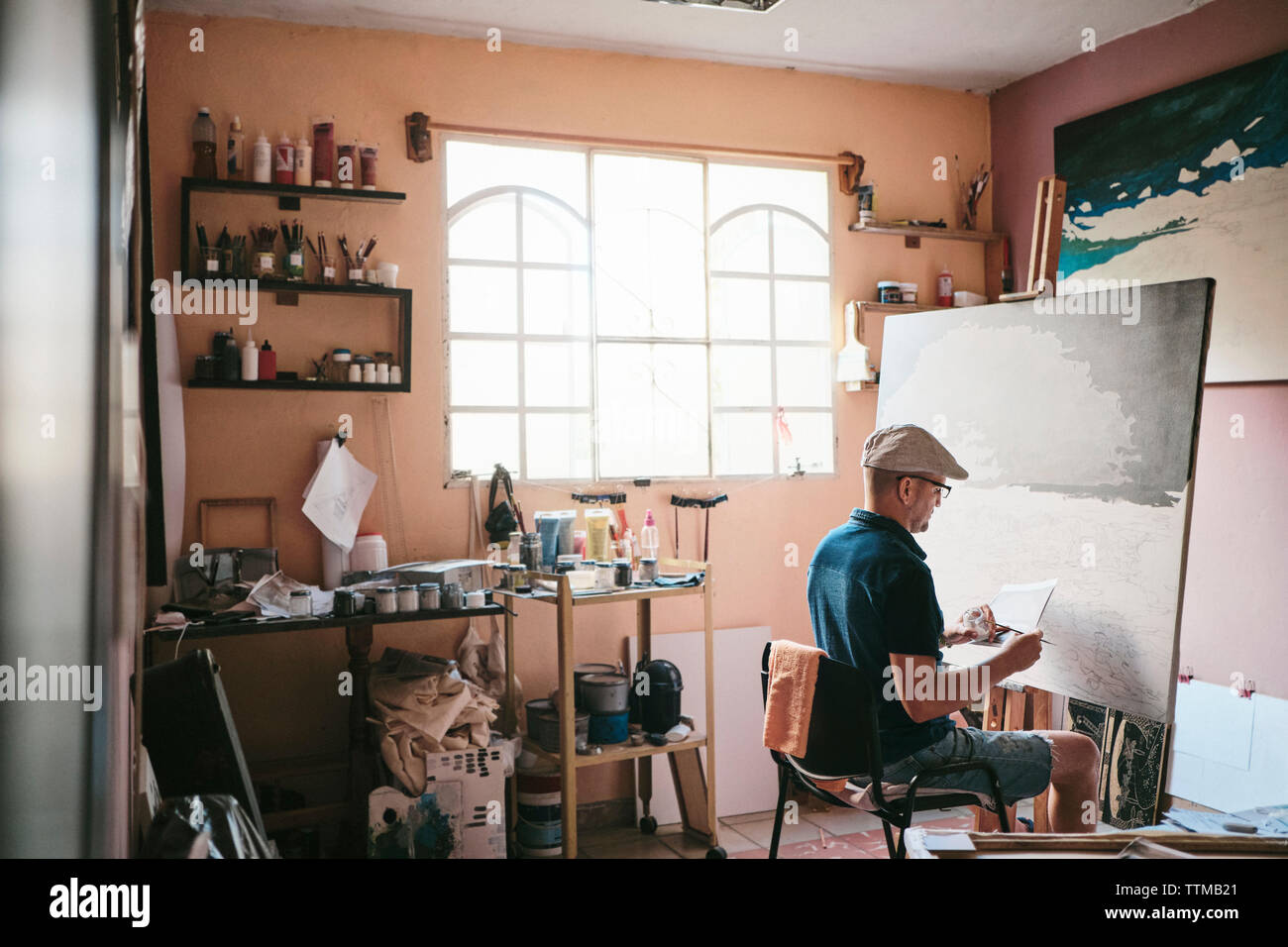 Mitte der erwachsene Mann arbeiten als Maler mit Pinsel und Leinwand in seinem Studio Stockfoto