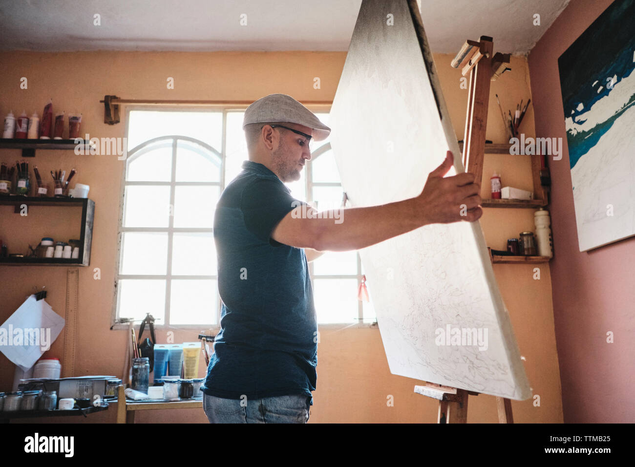 Mitte der erwachsene Mann arbeitet als Maler die Leinwand auf staffelei in seinem Studio Stockfoto