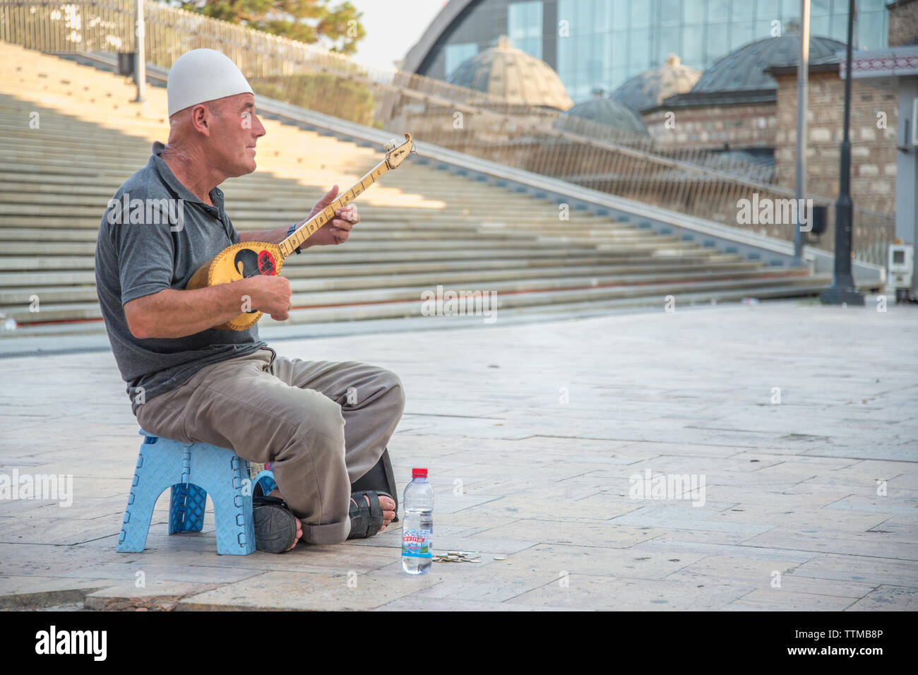 Älterer Mann spielt Musik auf einem massivem Messing Saiteninstrument, ausserhalb in den alten Basar von Skopje sitzen. Stockfoto