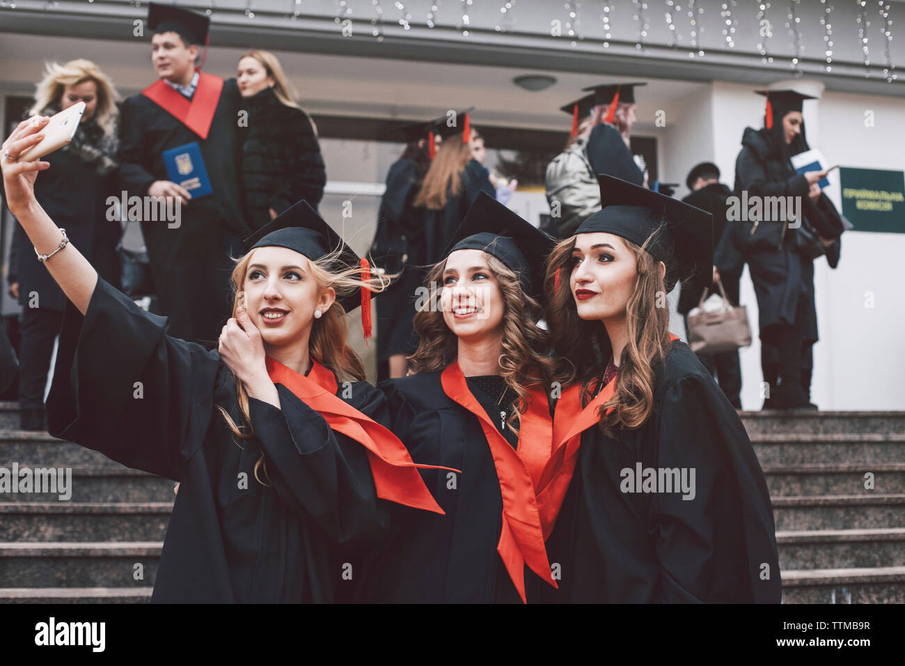 Gerne weibliche Freunde tragen Graduierung Kleider unter selfie beim Stehen auf Schritte Stockfoto