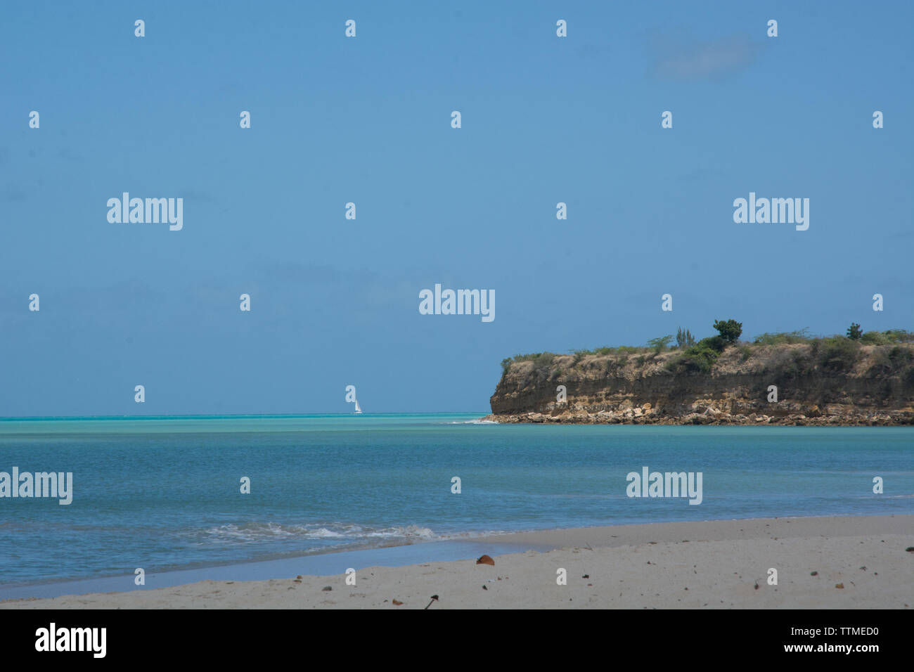 Einen karibischen Strand mit kristallklarem, blauen Wasser. Schönen blauen Himmel und unberührten, goldenen Sand. Segelyacht im Hintergrund Stockfoto