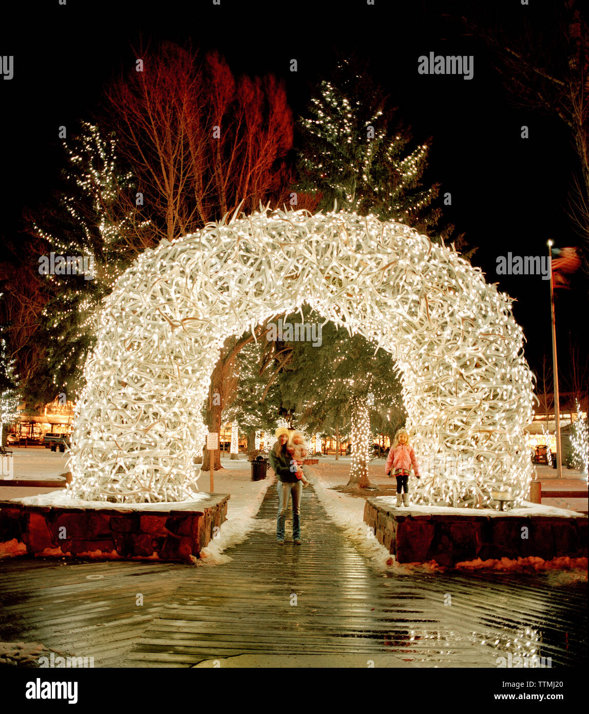 USA, Wyoming Jackson Hole, Mutter und Kinder stehen unter einem Bogen der Geweihe in der Innenstadt von Jackson Hole gemacht Stockfoto