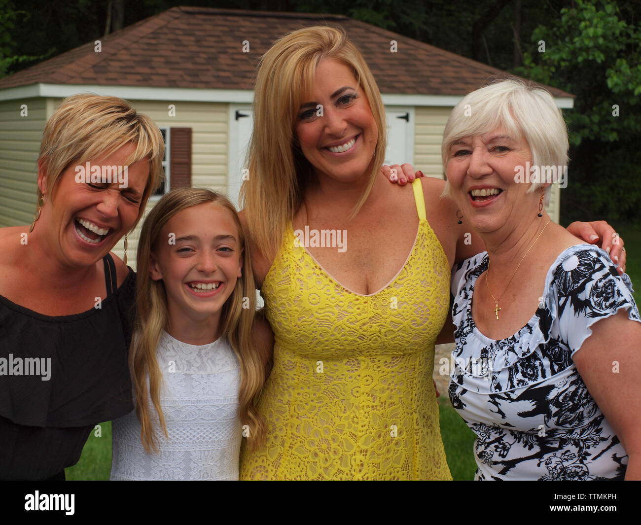 Vier sehr glücklich lächelnde Frauen der gleichen Familie mit sehr großen Lächeln. Mutter und zwei Töchtern mit kleinen Enkelin. Stockfoto