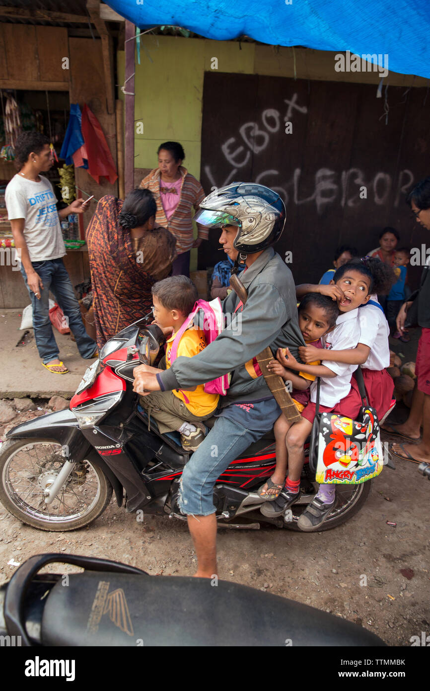 Indonesien, Flores, ein Vater und seine drei Söhne fahren mit dem Motorrad an der Bajawa Markt in Bajawa Stockfoto
