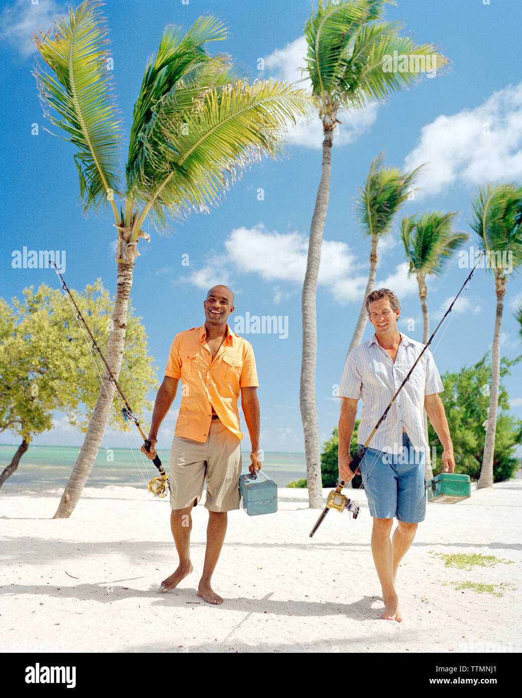 USA, Florida, zwei Männer zu Fuß am Strand mit Angelruten und Boxen angehen, Islamorada Stockfoto