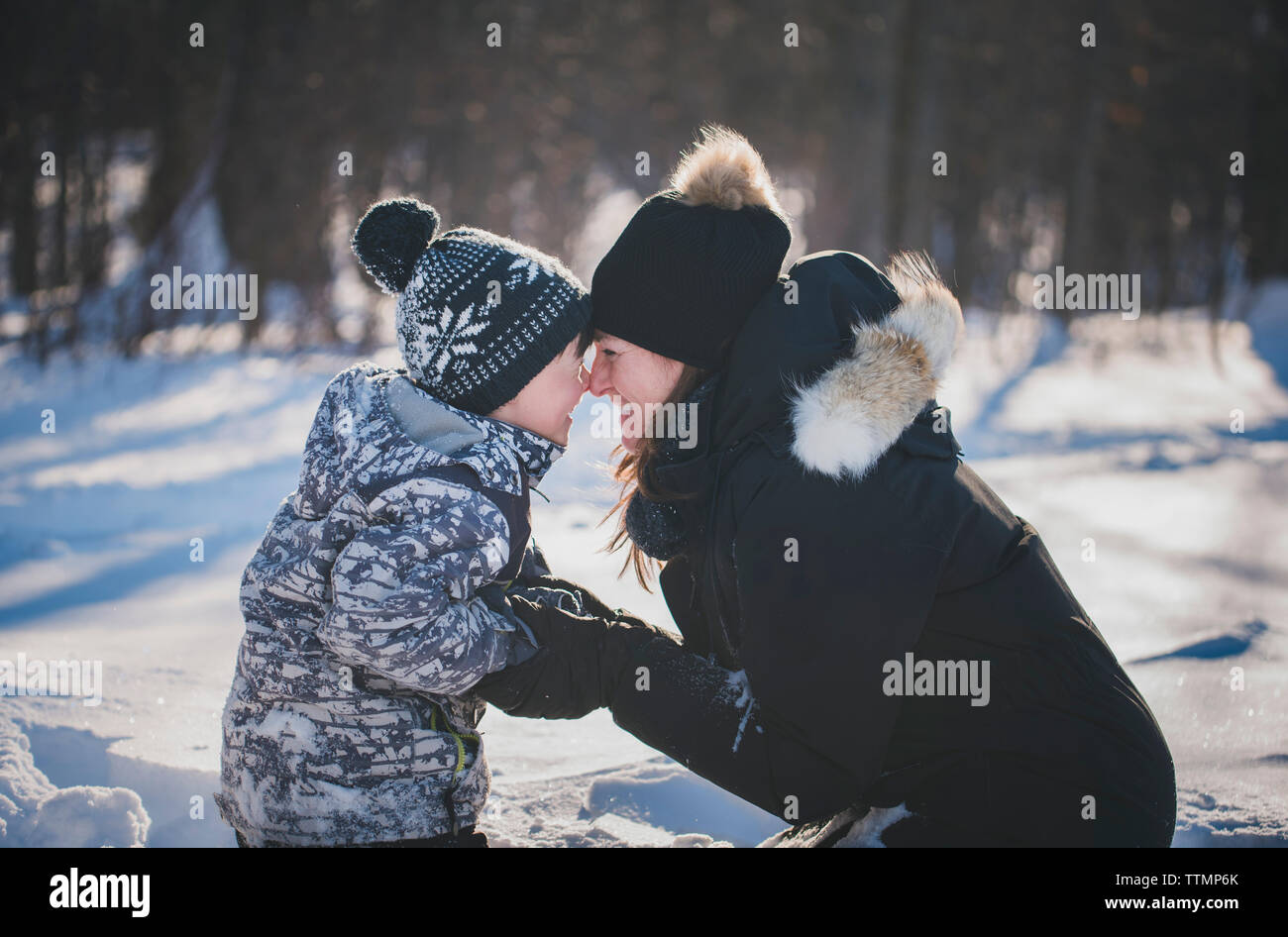 Verspielte Mutter und Sohn reiben Nasen auf schneebedeckten Feld Stockfoto