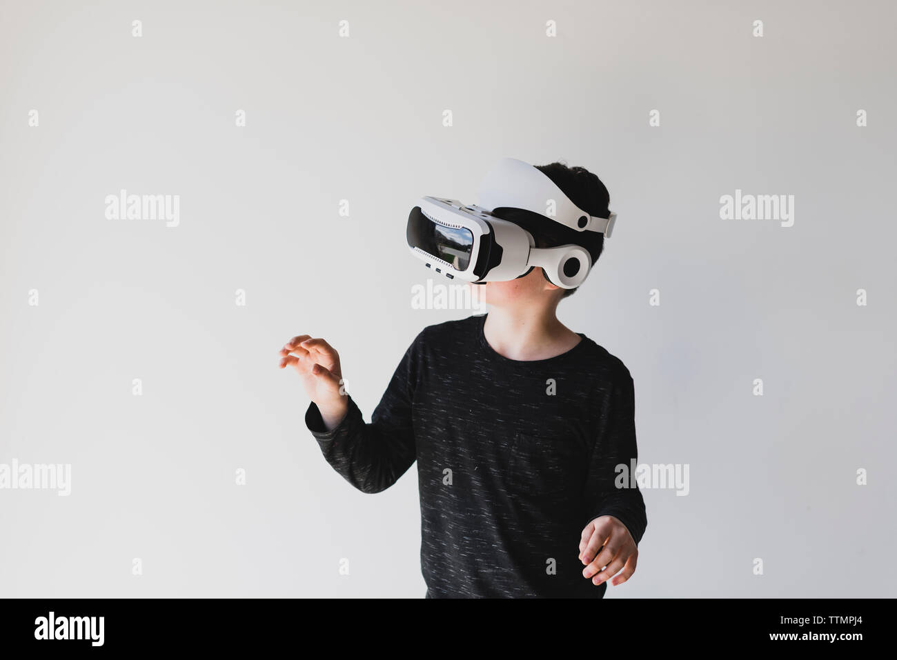 Junge mit Virtual Reality beim Stehen vor weißem Hintergrund Stockfoto