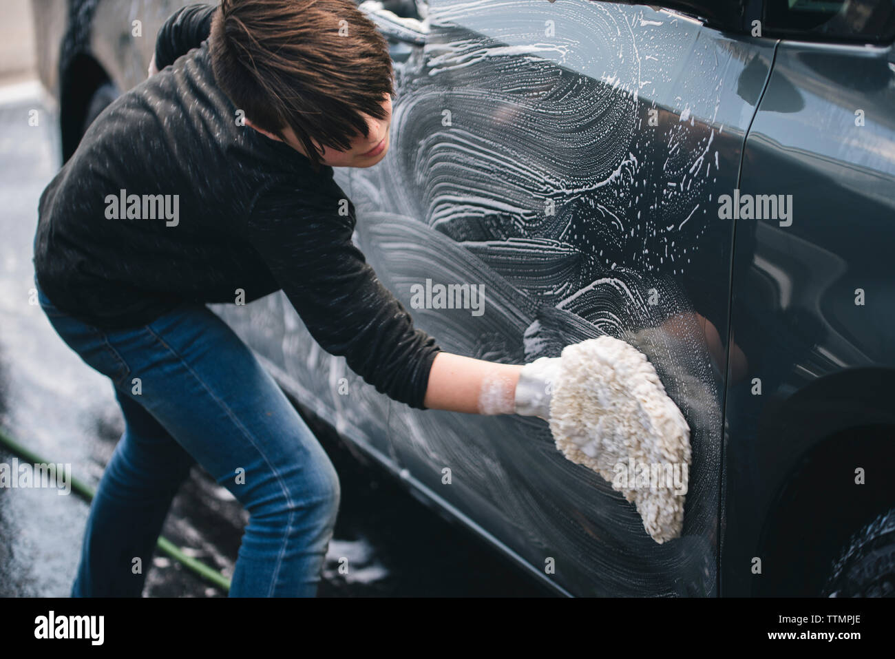 Seitenansicht des Jungen waschen Auto in der Einfahrt Stockfoto