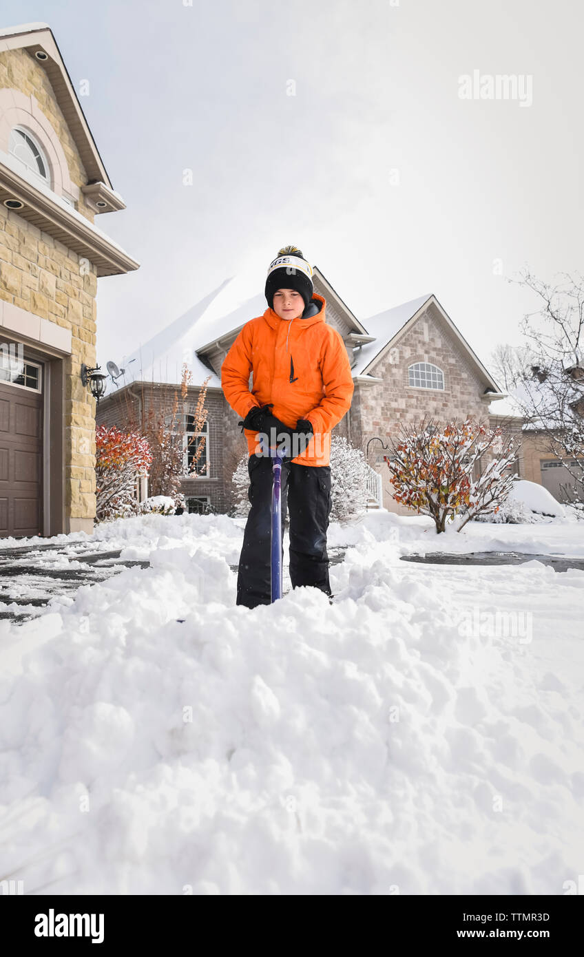 Heranwachsenden Jungen Schneeschaufeln aus der Fahrstraße nach einem Wintersturm Stockfoto