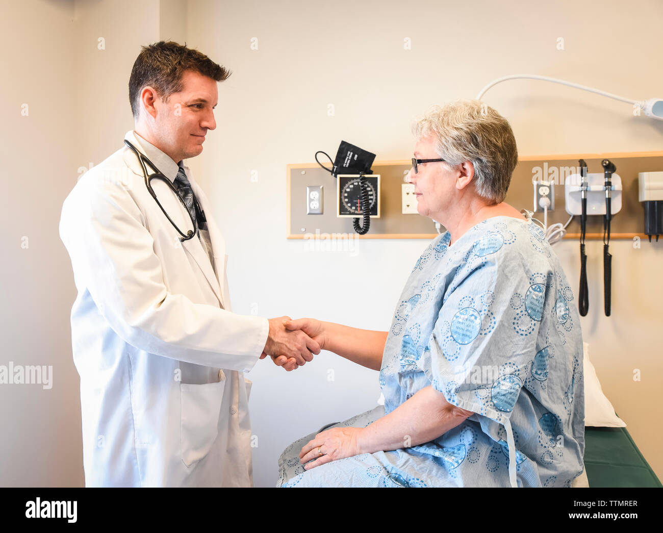 Arzt die Hände schütteln mit älteren Patienten mit Kleid in der Klinik. Stockfoto