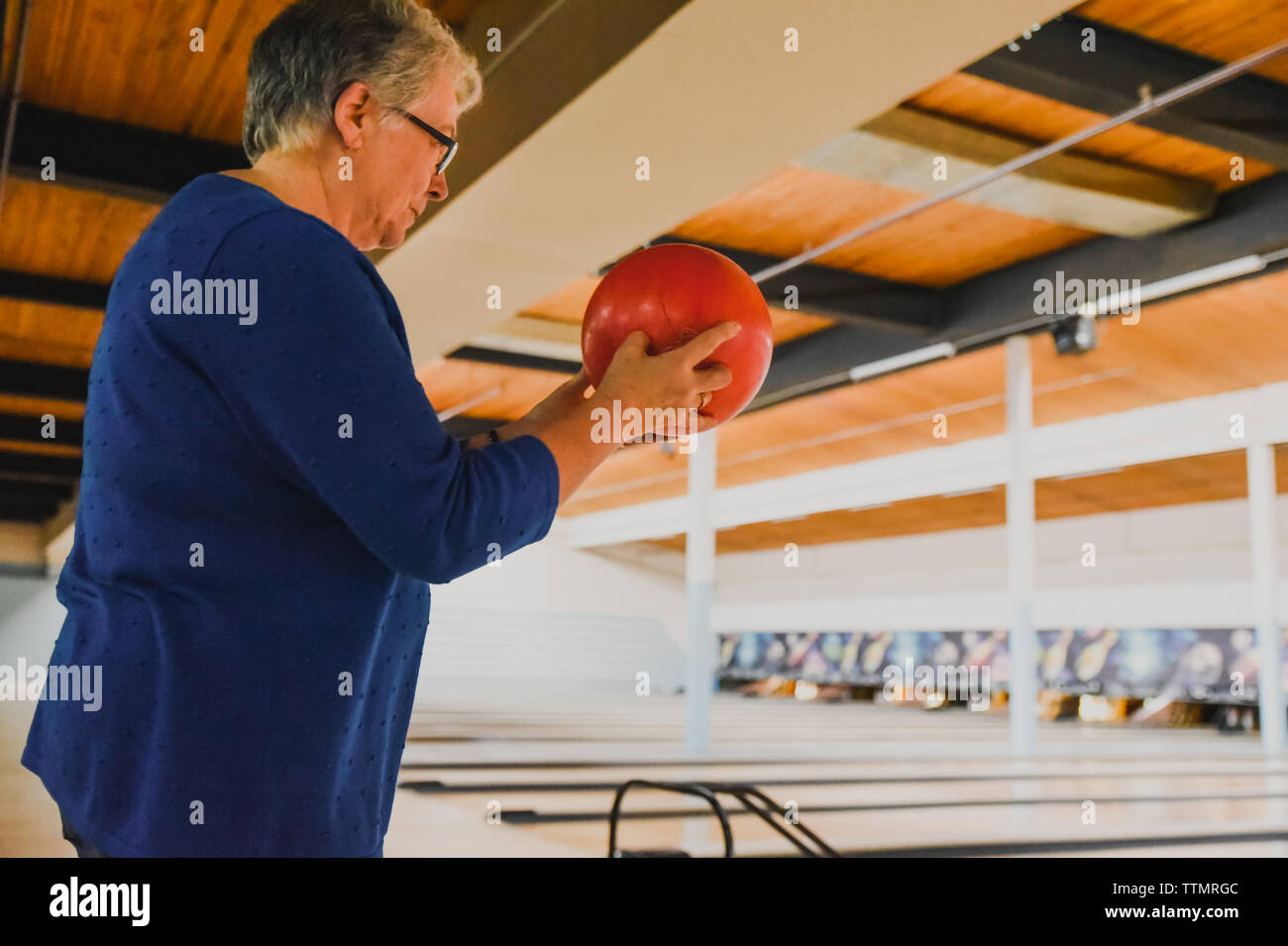 Ältere Frau mit Bowling Ball und Fokussierung auf Bowling Pins. Stockfoto
