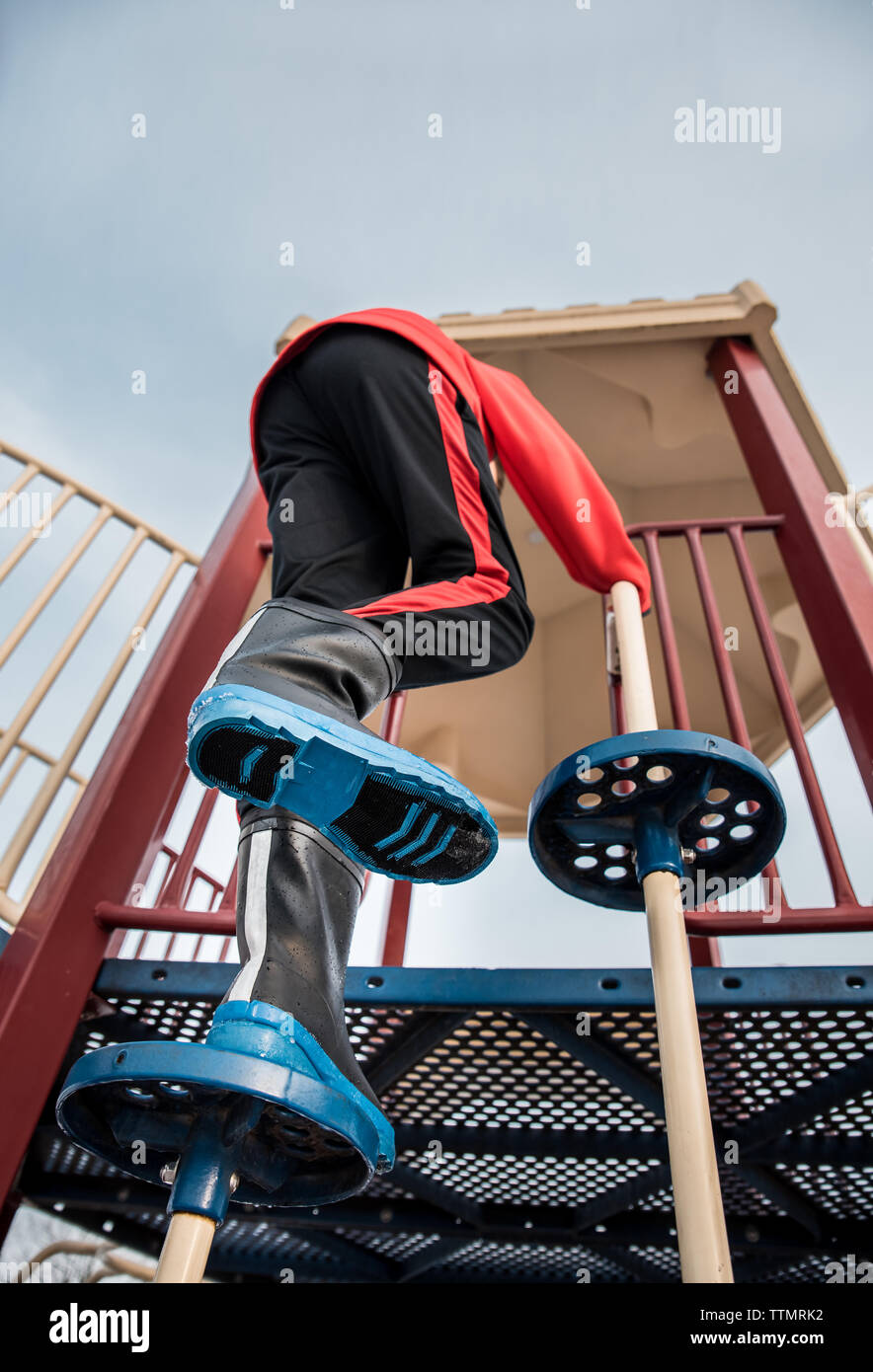 Niedrigen Winkel schließen, bis der junge klettern Spielplatz Struktur in regen Stiefel. Stockfoto