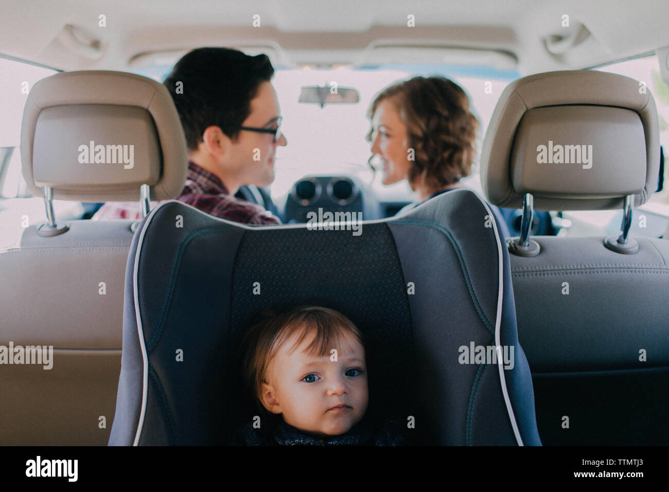 Mama und Papa fahren in weißes Auto mit Baby im Auto Sitz auf der Rückseite Stockfoto