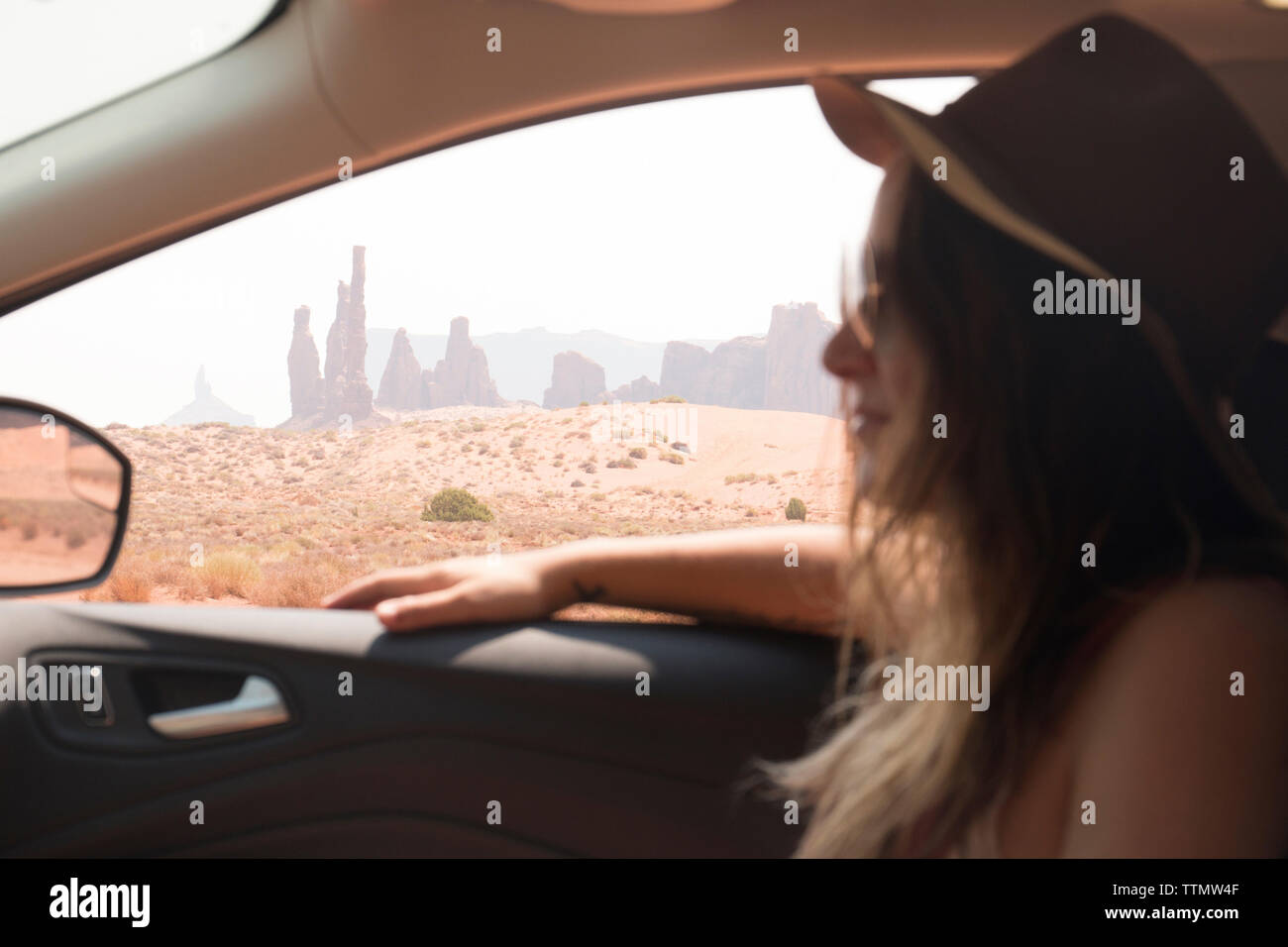 Seitenansicht der Frau mit Hut und Sonnenbrille beim Sitzen im Auto am Monument Valley Tribal Park Stockfoto