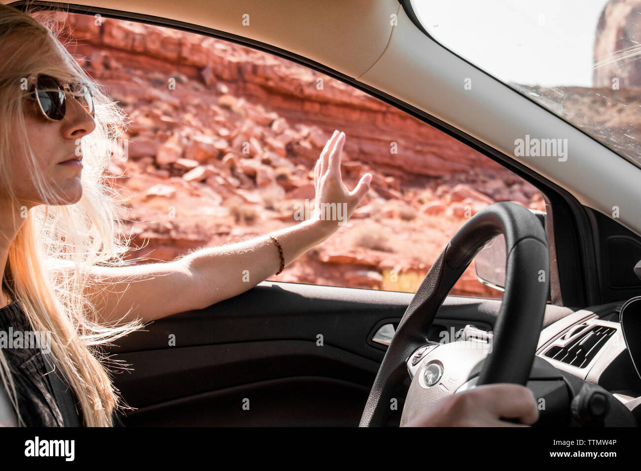 Frau mit Sonnenbrille gestikuliert während der Fahrt Auto am Monument Valley Tribal Park Stockfoto
