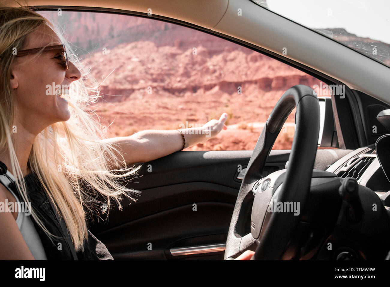 Glückliche Frau Sonnenbrille tragen gestikuliert während der Fahrt Auto am Monument Valley Tribal Park Stockfoto
