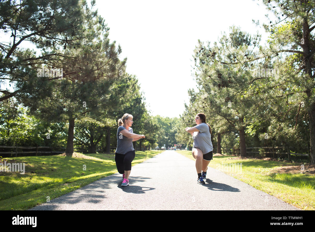 Mutter und Tochter stretching Arme und Beine auf Fußweg im Park während der sonnigen Tag Stockfoto