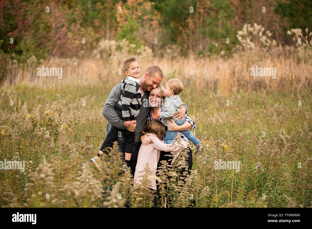 Glückliche Eltern, der Kinder beim stehen inmitten von Pflanzen gegen Bäume im Wald Stockfoto