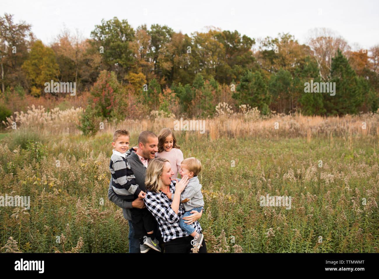 Glückliche Eltern mit Kindern steht man inmitten Pflanzen gegen Bäume im Wald Stockfoto