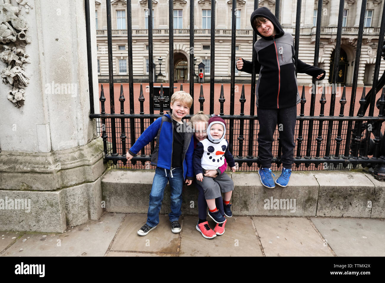 Vier Geschwister Sitzen am Tor der Buckingham Palace Stockfoto