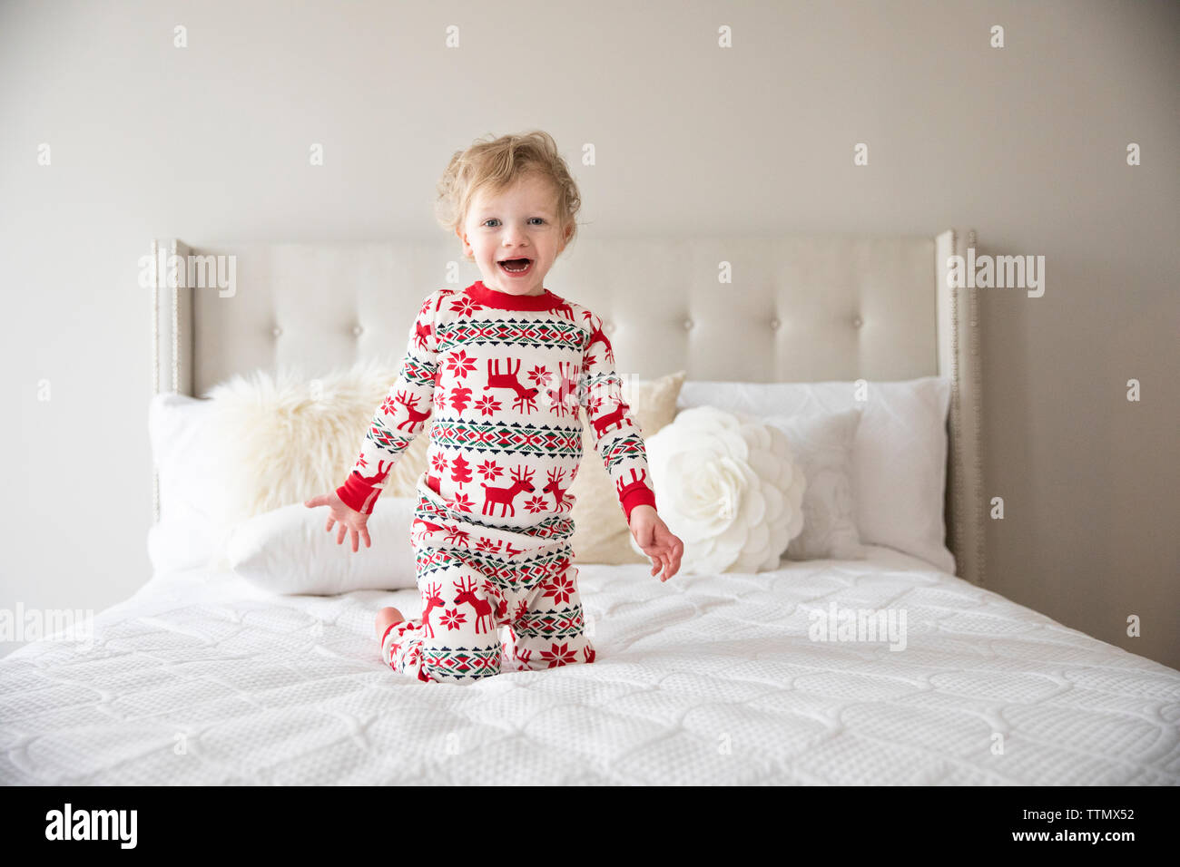 Happy Toddler Boy tragen Urlaub Schlafanzug springt auf weißen Bett Stockfoto