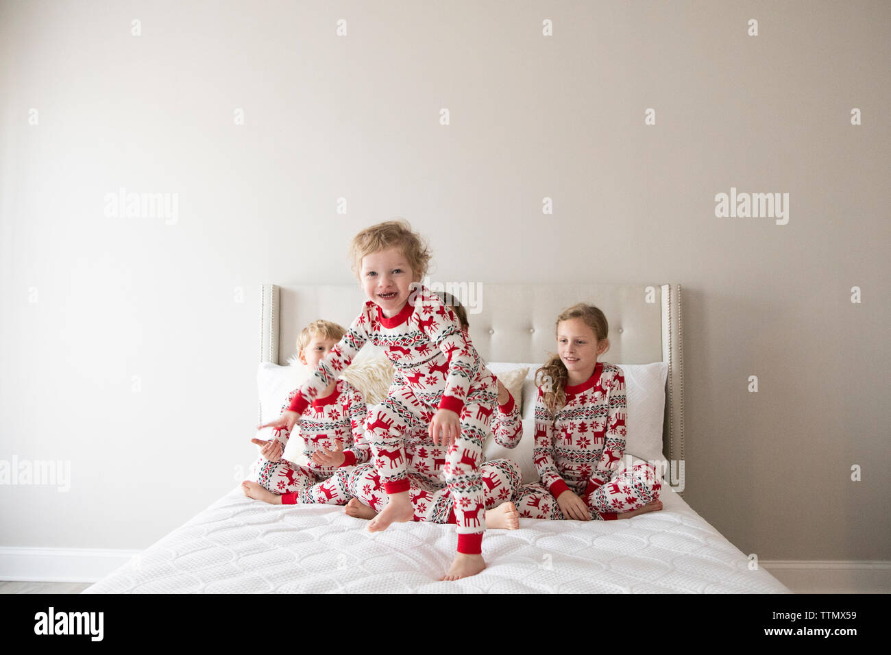 Vier Glückliche Geschwister in Urlaub Schlafanzug sitzen auf weißen Bett Stockfoto