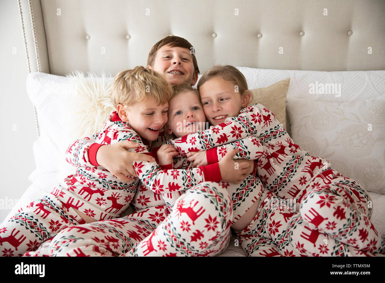 Vier Kleinkind zu Tween Geschwister in Urlaub Schlafanzug Schmusen auf dem Bett Stockfoto